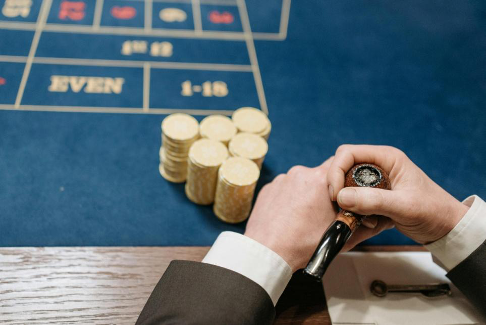 Close-up view of stacked casino chips and a guest holding a cigar during an elegant gaming moment.