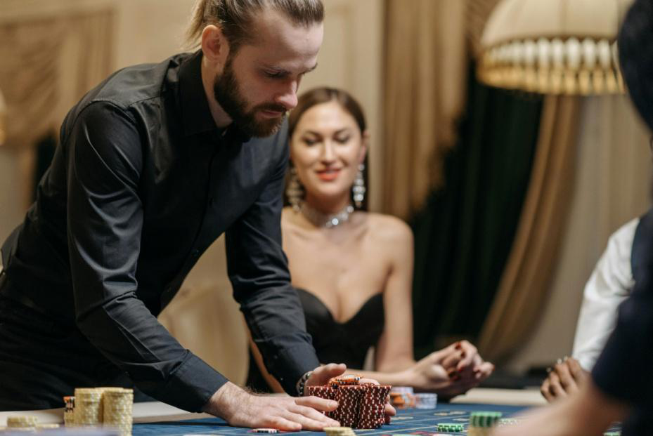 A dealer organizing chips on a casino table while guests enjoy an elegant gaming experience.