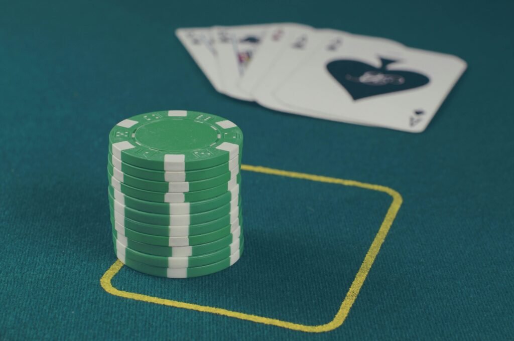 Stack of green poker chips on a casino table with playing cards in the background